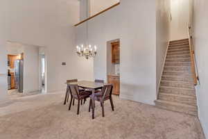 Carpeted dining area featuring sink, a notable chandelier, and a towering ceiling