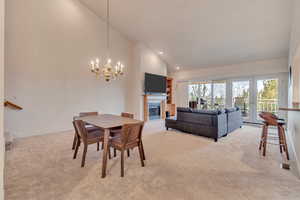 Dining area with french doors, high vaulted ceiling, light carpet, and a notable chandelier