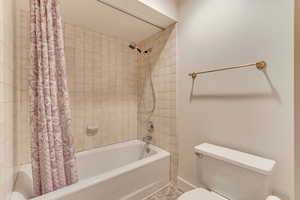 Bathroom featuring shower / tub combo with curtain and toilet