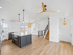 Kitchen with stainless steel appliances, white cabinetry, a kitchen island, and decorative light fixtures