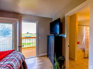 Bedroom featuring access to outside, ensuite bath, and light hardwood / wood-style floors