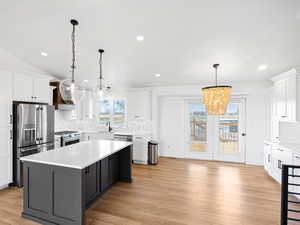 Kitchen with pendant lighting, sink, white cabinetry, premium appliances, and a kitchen island