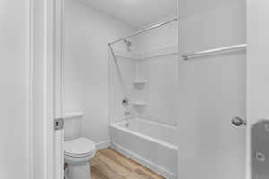 Bathroom featuring wood-type flooring, toilet, and bathing tub / shower combination