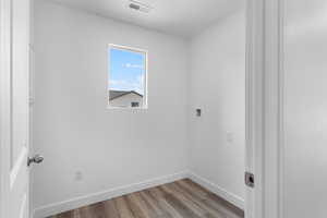 Washroom with hookup for a washing machine and light hardwood / wood-style floors