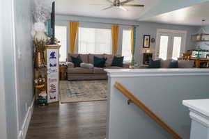 Living room featuring vaulted ceiling, ceiling fan, and dark hardwood / wood-style flooring