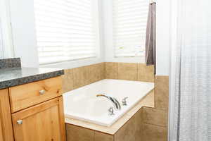 Bathroom with vanity and tiled bath