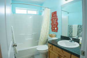 Full bathroom featuring vanity, shower / bath combination with curtain, and toilet