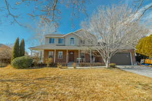 View of front of house featuring a garage, a front lawn, and a porch