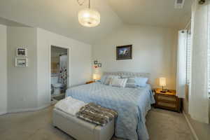 Carpeted bedroom featuring lofted ceiling and connected bathroom