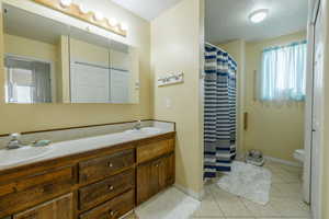 Bathroom with a healthy amount of sunlight, toilet, tile patterned flooring, and vanity