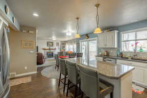 Kitchen featuring a fireplace, white cabinetry, sink, dark stone counters, and hanging light fixtures