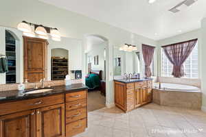 Bathroom with tile patterned flooring, vanity, backsplash, and tiled bath