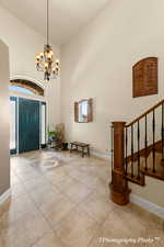 Tiled entrance foyer with a high ceiling, plenty of natural light, and an inviting chandelier