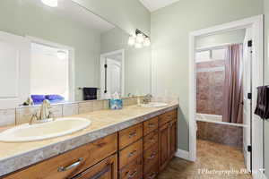 Bathroom featuring shower / tub combo with curtain, vanity, and tile patterned flooring