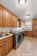 Washroom with washer and dryer, sink, light tile patterned floors, and cabinets