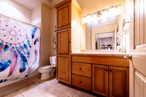 Full bathroom featuring vanity, tile patterned floors, shower / bath combo with shower curtain, and toilet