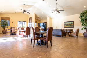 Tiled dining space with ceiling fan and high vaulted ceiling