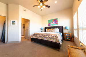 Carpeted bedroom with vaulted ceiling and ceiling fan