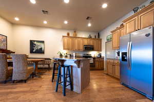 Kitchen featuring stainless steel appliances, a breakfast bar, dark stone countertops, and light wood-type flooring