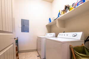 Laundry room featuring separate washer and dryer, electric panel, and light tile patterned flooring