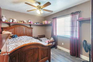 Bedroom with a textured ceiling, light hardwood / wood-style flooring, and ceiling fan