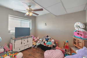 Playroom featuring dark hardwood / wood-style flooring, a paneled ceiling, and ceiling fan