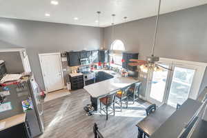 Kitchen with appliances with stainless steel finishes, high vaulted ceiling, decorative light fixtures, hardwood / wood-style flooring, and ceiling fan