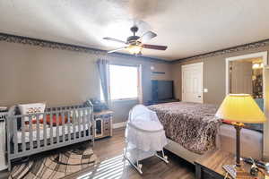 Bedroom with ceiling fan, wood-type flooring, and a textured ceiling