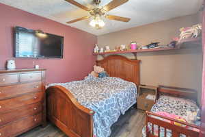 Bedroom featuring ceiling fan, hardwood / wood-style floors, and a textured ceiling