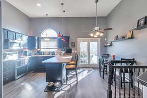 Kitchen with dark wood-type flooring, blue cabinetry, stainless steel appliances, a kitchen breakfast bar, and decorative light fixtures