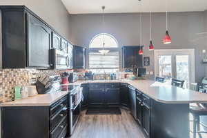 Kitchen with appliances with stainless steel finishes, a kitchen breakfast bar, kitchen peninsula, and hanging light fixtures