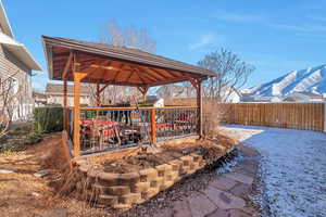 Snow covered patio featuring a mountain view and a gazebo