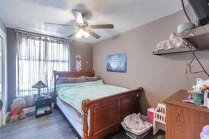 Bedroom with multiple windows, ceiling fan, and dark hardwood / wood-style flooring