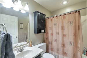 Full bathroom with vanity, shower / tub combo with curtain, and toilet