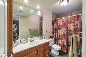 Bathroom with vanity, curtained shower, tile patterned floors, and toilet