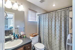 Bathroom featuring a shower with curtain, vanity, and toilet