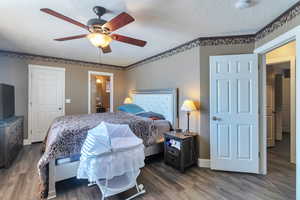 Bedroom featuring ceiling fan, dark hardwood / wood-style floors, and a textured ceiling