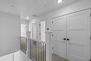 Hall featuring light colored carpet and a textured ceiling