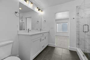 Bathroom with vanity, a shower with shower door, and toilet