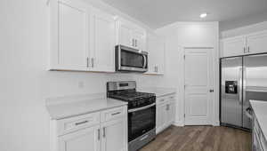 Kitchen featuring appliances with stainless steel finishes, white cabinets, and dark hardwood / wood-style flooring