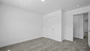 Unfurnished bedroom featuring dark carpet