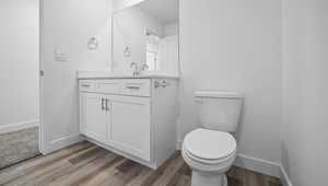 Bathroom featuring vanity, hardwood / wood-style flooring, and toilet