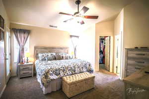 Primary bedroom with a walk in closet, lofted ceiling, ceiling fan, and a closet