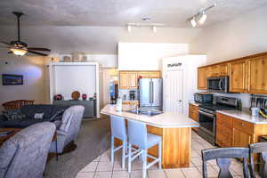 Kitchen with vaulted ceiling, sink, a breakfast bar area, light tile patterned floors, and stainless steel appliances