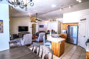 Kitchen with high quality fridge, ceiling fan with notable chandelier, lofted ceiling, sink, and a kitchen island with sink