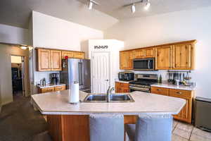 Kitchen featuring a kitchen island with sink, sink, a kitchen bar, and appliances with stainless steel finishes