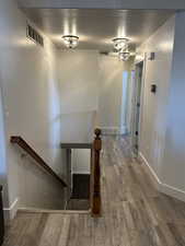 Stairway with wood-type flooring and a textured ceiling