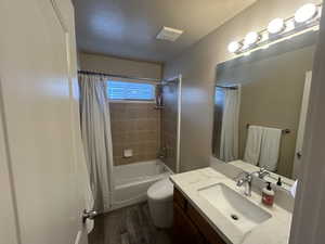 Full bathroom featuring toilet, wood-type flooring, shower / bathtub combination with curtain, and vanity