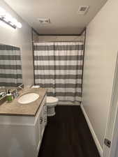 Bathroom with hardwood / wood-style flooring, a shower with shower curtain, vanity, a textured ceiling, and toilet