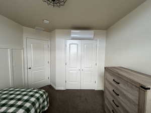 Carpeted bedroom featuring a closet and an AC wall unit